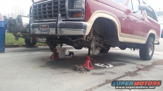 1980 Ford Bronco front end disassembled on jack stands, brake components removed