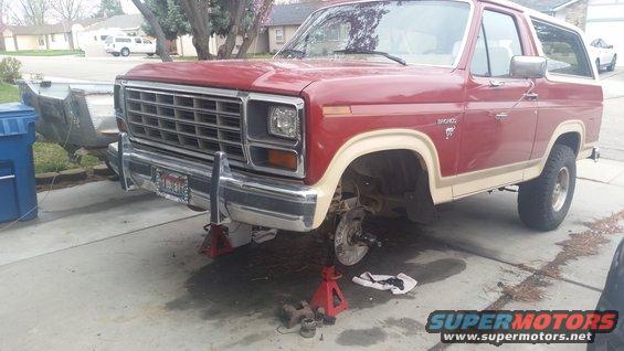 Red Bronco on jack stands, front wheels off, brake work in progress