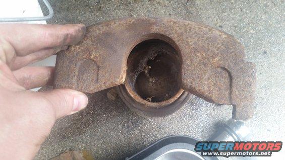 Rusted brake caliper held by a hand, showing internal corrosion and cobwebs