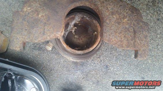 Rusted brake caliper and rotor assembly on asphalt