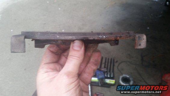 Worn brake pad held in hand, with tools in background