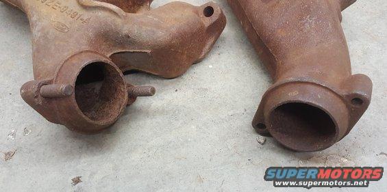 Two rusty exhaust manifolds with Ford markings, one showing part number 32E-9491-A