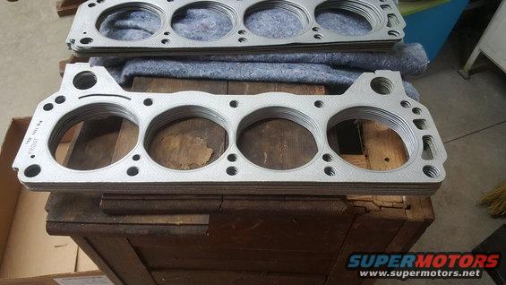 Stack of new engine head gaskets, some with 'FRONT' and part numbers visible