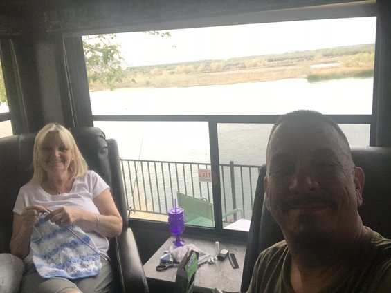 Man and woman sitting in chairs inside an RV, looking out at a lake