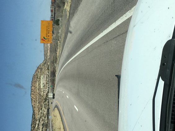 Highway sign says 'Welcome to New Mexico'. View from inside a vehicle
