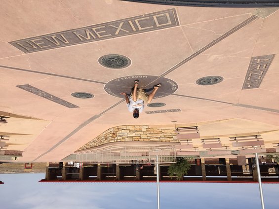 Person standing at the Four Corners Monument, with state names inscribed on the ground