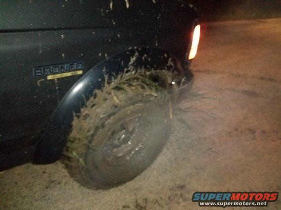 Rear tire and fender of a dark SUV at night