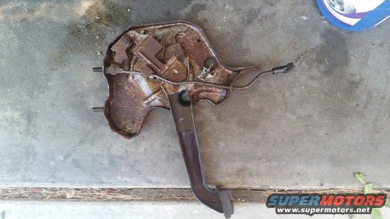 Rusty clutch pedal assembly with linkage and electrical connector, lying on concrete