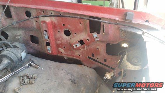 Close-up of a red vehicle's engine bay firewall with some wiring and a socket wrench