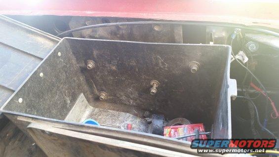 Underhood toolbox with some tools and a box of parts inside. Red vehicle body visible above