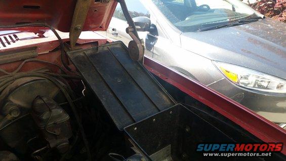Underhood toolbox in red vehicle, with a silver car visible behind
