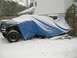 1986 Ford Bronco - A partially covered SUV sits in the snow, its tires and front fender visible.