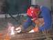 1986 Ford Bronco - A person is welding metal outdoors, wearing protective gear and a decorative welding mask.