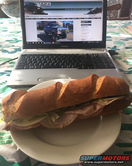Laptop open to FSB website showing Ford trucks, with a sandwich on a plate in front