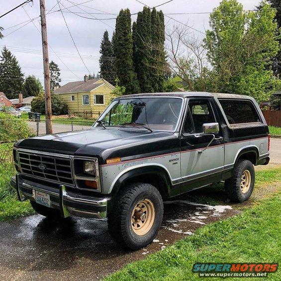 Black and silver Ford Bronco parked on a wet driveway. License plate reads BAX4202