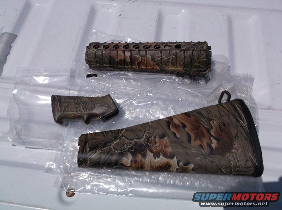 Camouflage rifle forend, pistol grip, and buttstock laid out on a white surface