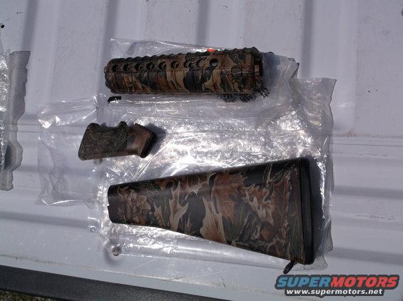 Camouflage rifle forend, pistol grip, and buttstock laid out on a white surface