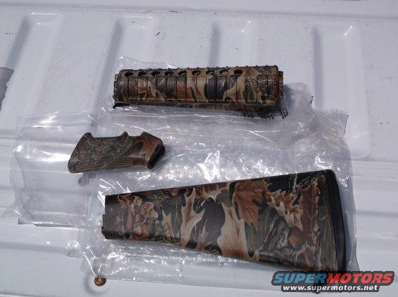 Camouflage gun stock, handguard, and grip parts on a white surface