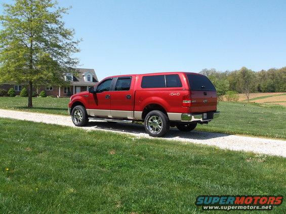 Red 2008 Ford F-150 with camper shell parked on gravel driveway