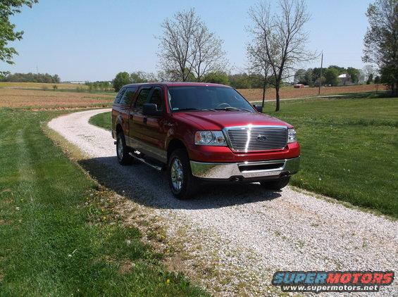 Red pickup truck with camper shell on a gravel driveway