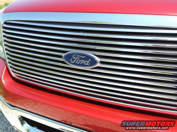 Close-up of a red Ford F-Series truck grille with a chrome surround and the Ford oval logo