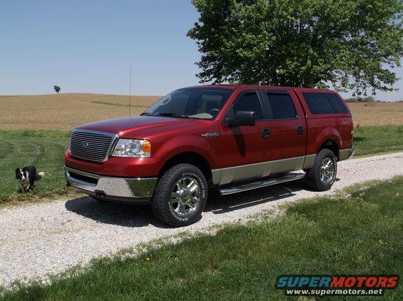 Red 2008 Ford F-150 with camper shell parked on a gravel driveway