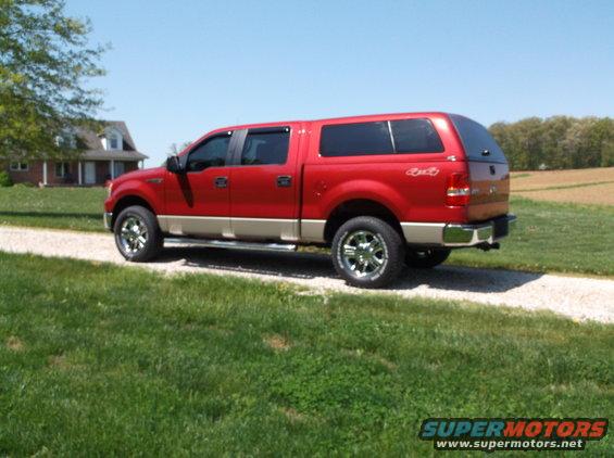 Red 2008 Ford F-150 pickup truck with a cap, parked on a gravel driveway