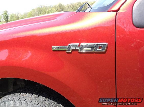 Close-up of a red Ford F-150 fender with an F-150 badge. The Supermotors.net watermark is visible