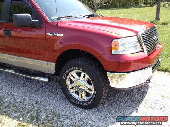 Red Ford F-150 truck, front passenger side, chrome wheels, chrome bumper, gravel lot