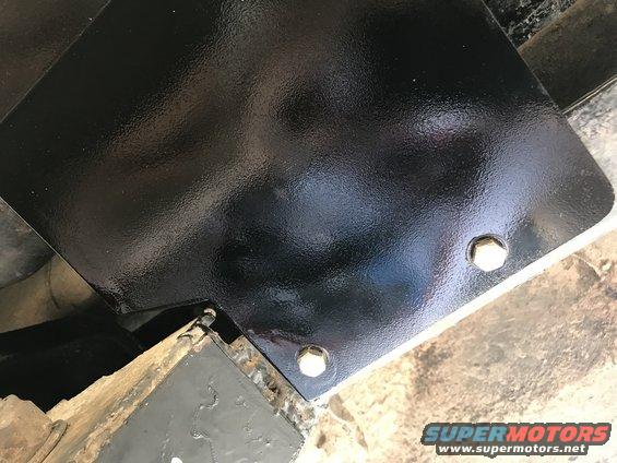 Close-up of black painted metal part bolted to frame