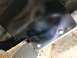 1989 Ford Bronco - This photo shows a close-up of a black painted metal component attached with bolts to the undercarriage of a vehicle.