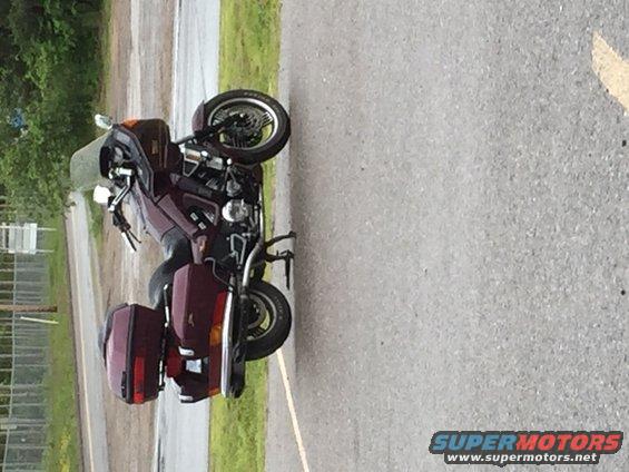 Maroon touring motorcycle with saddlebags parked on asphalt