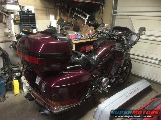 Maroon touring motorcycle with saddlebags and trunk parked in a garage