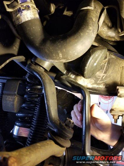 Close-up of a vehicle's suspension and steering linkage with a hand present