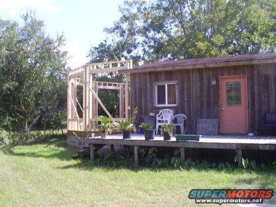 house with wooden deck and new room framing on left