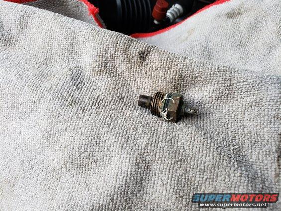 Engine sensor resting on a gray towel. Some engine parts are visible in the background