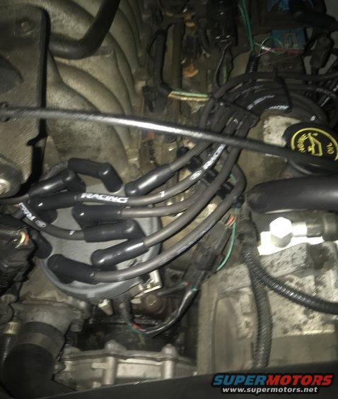 Engine compartment showing distributor cap, spark plug wires labeled 'RACING', and various hoses and connectors