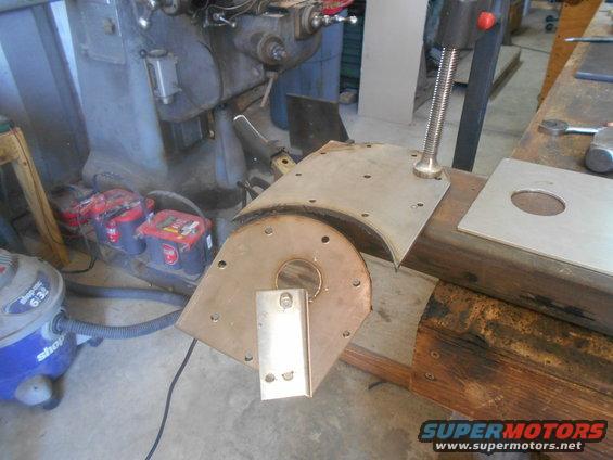 Metal fabrication parts on a workbench next to a milling machine and shop vacuum