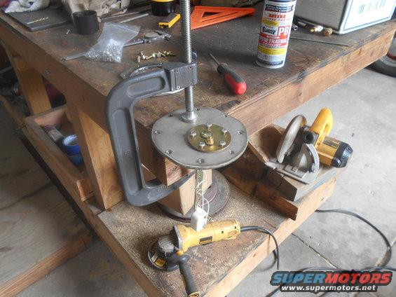 Fuel pump assembly clamped to workbench with angle grinder and circular saw
