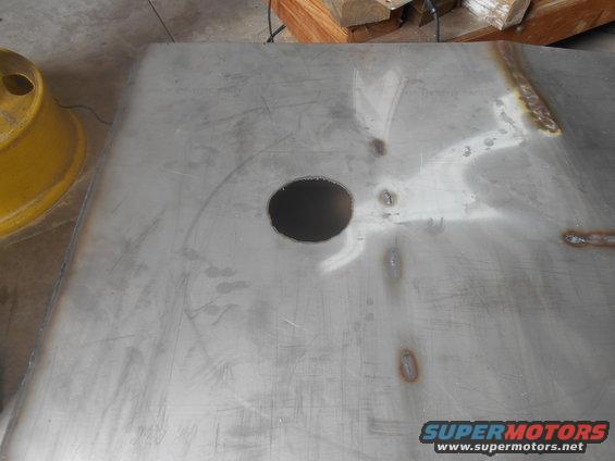 Metal fuel tank with a circular opening and visible weld marks