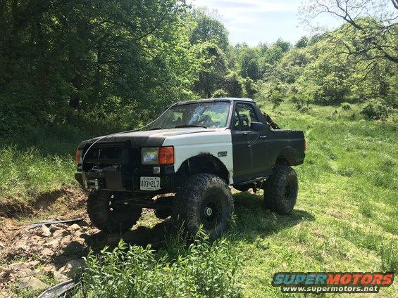 Two-tone 1989 Ford Bronco with off-road tires and a winch on the front bumper