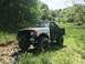 1989 Ford Bronco - A modified 1989 Ford Bronco sits in a grassy, wooded area with its front end on a rocky path.