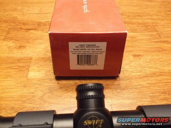 Swift Premier rifle scope box and scope on wooden surface. Box says Model 687M 4.5-14x, 44mm