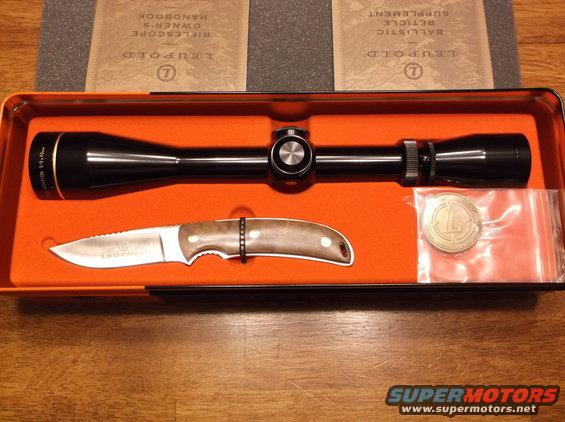 Leupold scope, knife, and coin in orange case. Owner's handbook visible
