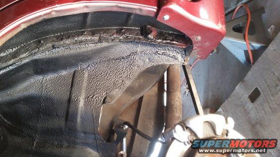 Undercarriage of a car, showing wheel well and suspension components. A jack stand is visible