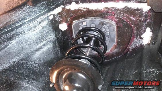 Close-up of a car's front strut assembly with black coil spring and metal mount