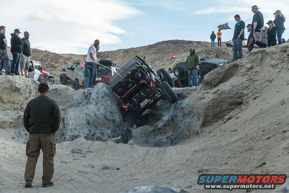 Off-road vehicle tilted on rocks, with spectators watching