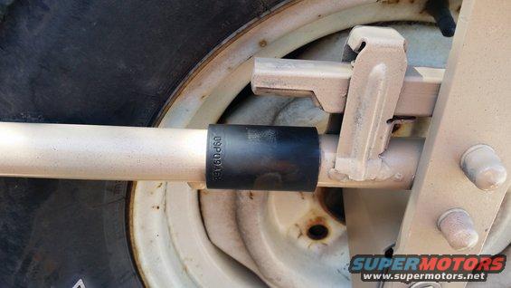 Close-up of a spare tire mount with a socket on a bar. Text on socket reads 09P0946