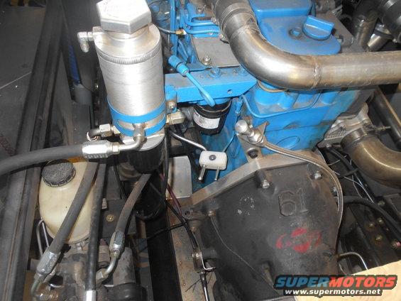 Engine compartment with blue engine block, silver oil filter housing, and metal pipes