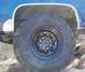 1979 Chevrolet C/K Pickup - A close-up view of a blue truck's wheel and fender, showing off-road tires and a chrome mud flap.
